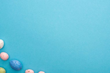 Mavi arka planda renkli tavuk ve bıldırcın yumurtalarının üst görüntüsü