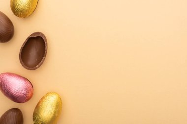 Top view of delicious chocolate eggs on beige background clipart