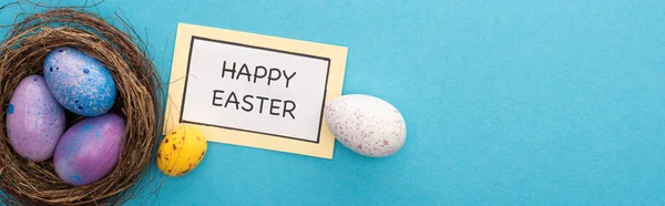 Kartın Yanında Paskalya Yumurtaları Olan Yuvalar Mavi Arka Planda Mutlu — Stok fotoğraf