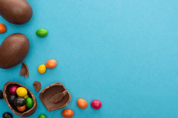 Bovenaanzicht Van Chocolade Paaseieren Met Kleurrijke Zoetigheden Blauwe Achtergrond — Stockfoto
