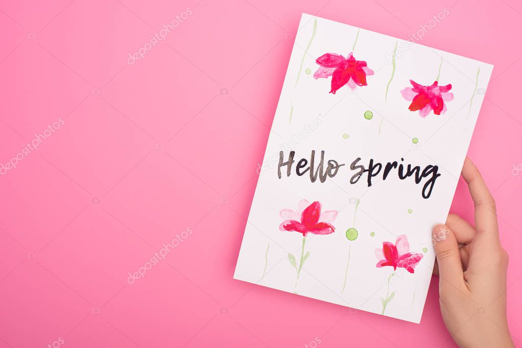 Cropped view of woman holding card with hello spring lettering on pink 