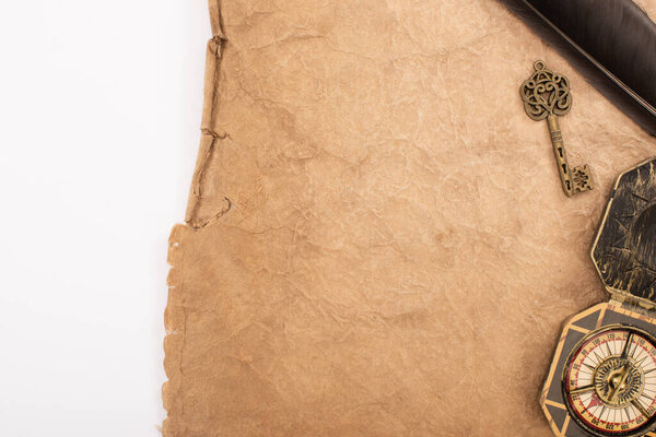 вид сверху на перо, винтажный ключ и компас на старой бумаге, изолированной на белом
