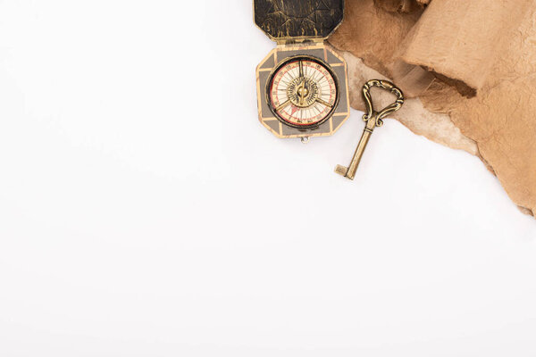 top view of vintage key, compass and aged paper isolated on white