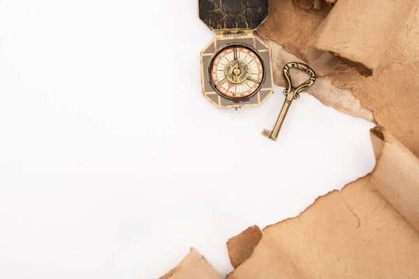 top view of vintage key, compass and aged paper isolated on white
