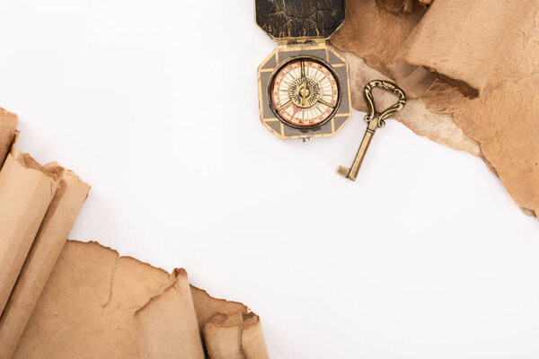top view of vintage key, compass and aged paper isolated on white
