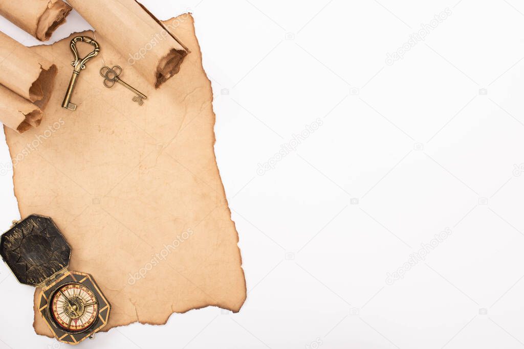 top view of vintage keys and compass on aged paper isolated on white