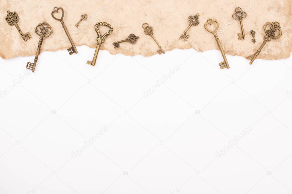 top view of vintage keys on aged paper isolated on white