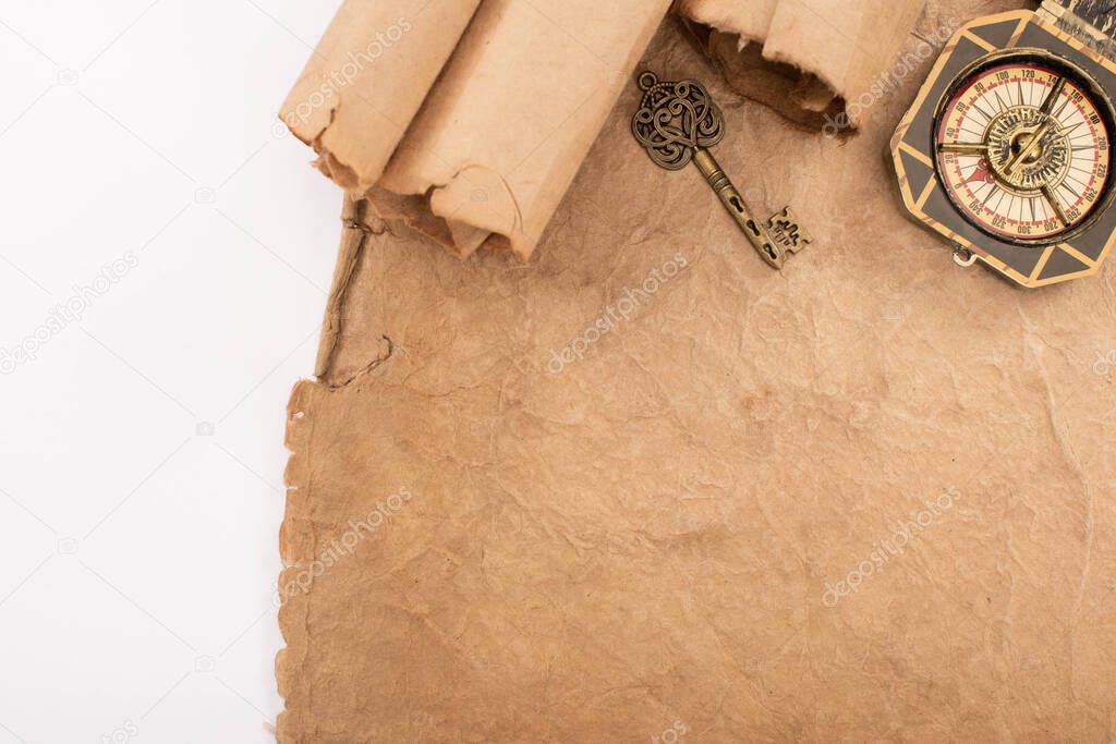 top view of vintage key and compass on aged paper isolated on white
