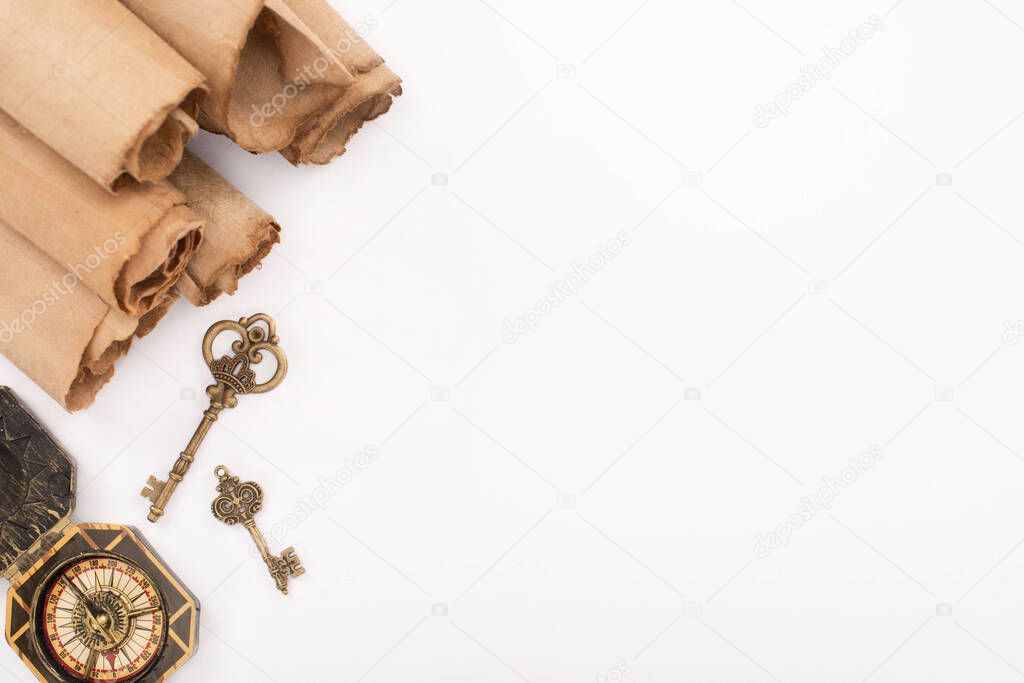 top view of vintage keys, compass and rolled aged paper isolated on white