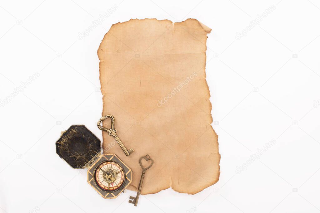 top view of vintage compass, keys on aged paper isolated on white