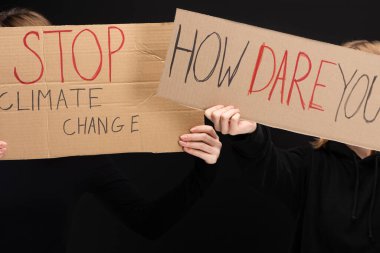 Cropped view of blondes with placards with stop climate change and how dare you lettering isolated on black, global warming concept clipart