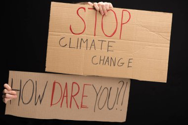 Cropped view of woman with placards with stop climate change and how dare you lettering isolated on black, global warming concept clipart