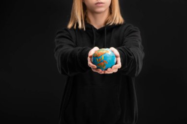Partial view of woman with outstretched hands holding plasticine globe isolated on black, global warming concept clipart