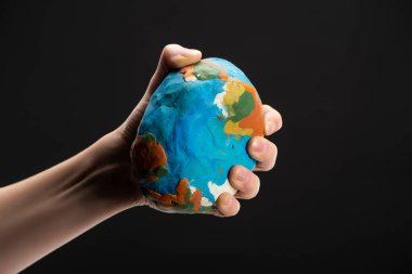 Cropped view of woman compressing plasticine globe in hand isolated on black, global warming concept clipart