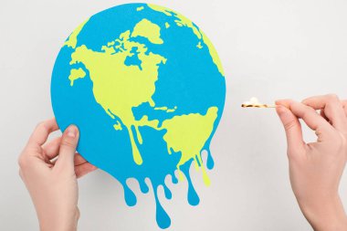 Cropped view of woman holding paper globe and match with fire on white, global warming concept clipart