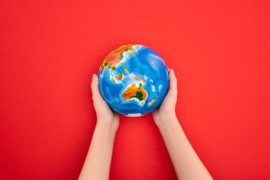 Cropped view of woman holding globe on red background, global warming concept clipart