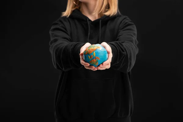 伸出手来抱着塑料球的女性形象被隔离在黑色的全球暖化的概念下 — 图库照片