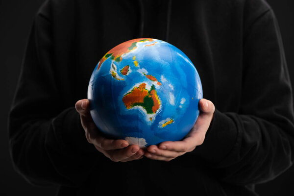 Cropped view of globe in female hands isolated on black, global warming concept