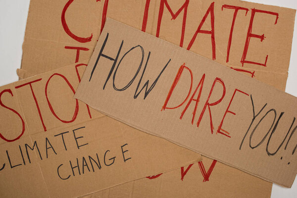 Top view of placards with how dare you, stop climate change, climate justice now lettering on grey, global warming concept