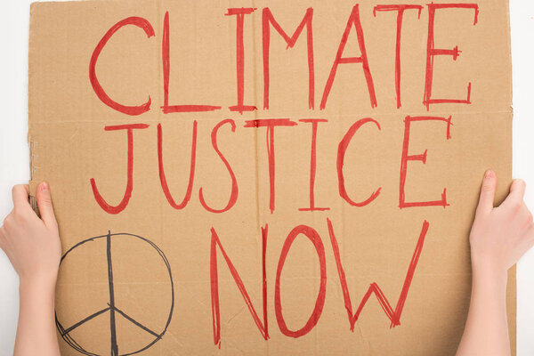 Cropped view of woman holding placard with climate justice now lettering on white background, global warming concept