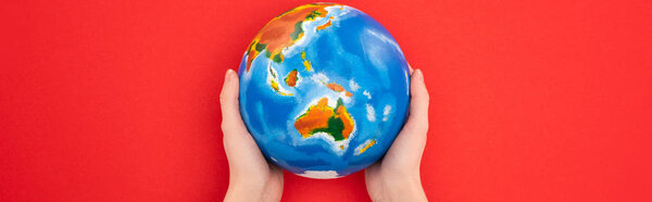 Panoramic view of woman holding globe isolated on red, global warming concept