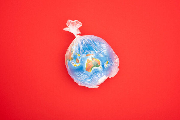 Top view of globe in plastic bag isolated on red, global warming concept