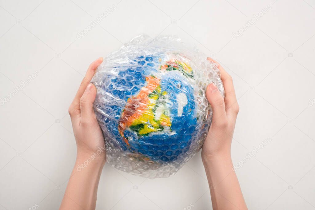 Cropped view of woman holding globe in plastic bag on white background, global warming concept