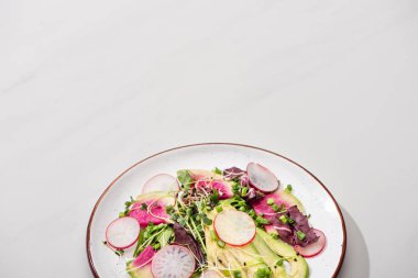 Taze turp salatası, yeşiller ve gri yüzeyde avokado.