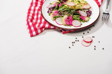 Taze turp salatası, yeşil salata ve beyaz yüzey üzerinde beyaz peçete ve çatalla birlikte avokado.