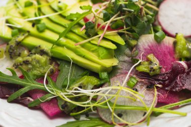 close up view of fresh radish salad with greens and avocado clipart