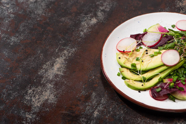 fresh radish salad with greens and avocado on plate on weathered surface