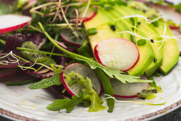 close up view of fresh radish salad with greens and avocado