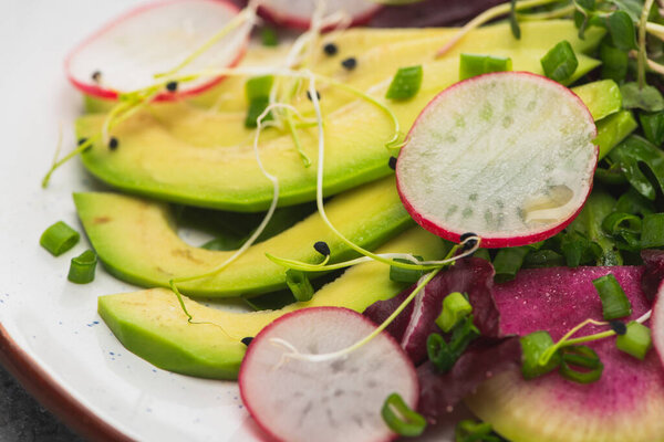 close up view of fresh radish salad with greens and avocado