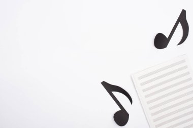 Müzik kitabı ve kağıt kesme notalarının beyaz arkaplan üzerindeki üst görünümü