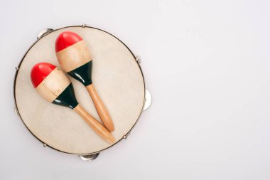 Top view of wooden maracas on tambourine on white background clipart