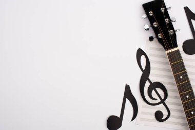 Top view of paper cut notes, music book and acoustic guitar on white background clipart
