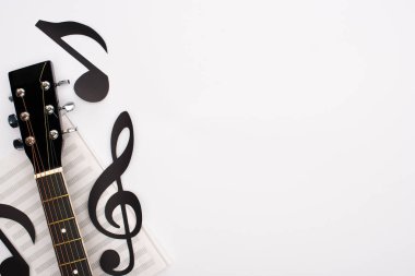Top view of paper cut notes, music book and acoustic guitar on white background clipart