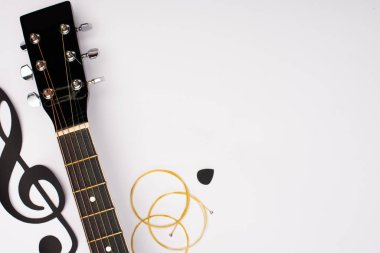 Akustik gitar ve kağıdın üst görünümü beyaz arkaplandaki müzik notasını keser