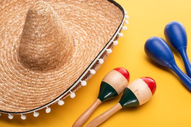 Sarı arka planda sombrero yakınlarında ahşap renkli ve mavi marakalar.