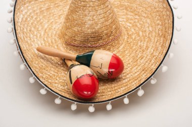 Close up view of maracas on sombrero on white background clipart