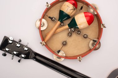 Top view of acoustic guitar near wooden maracas on tambourine on white background clipart