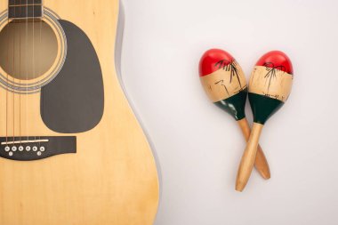 Top view of acoustic guitar near wooden maracas on white clipart