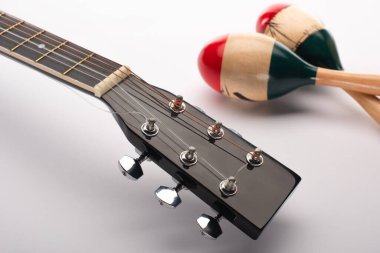 Akustik gitarın seçici odağı beyaz üzerine tahta marakas.