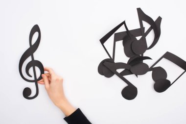 Siyah kağıtlı kadın elinin kısmi görünümü beyaz arkaplanda müzik notalarını kesiyor
