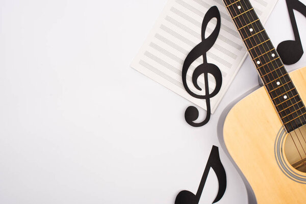Top view of paper cut notes with music book and acoustic guitar on white background