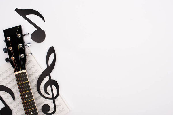 Top view of paper cut notes, music book and acoustic guitar on white background