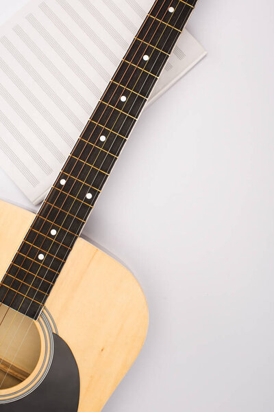 Top view of music book with acoustic guitar on white background