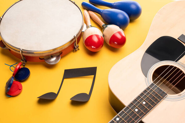 Musical instruments and paper cut music note on yellow background