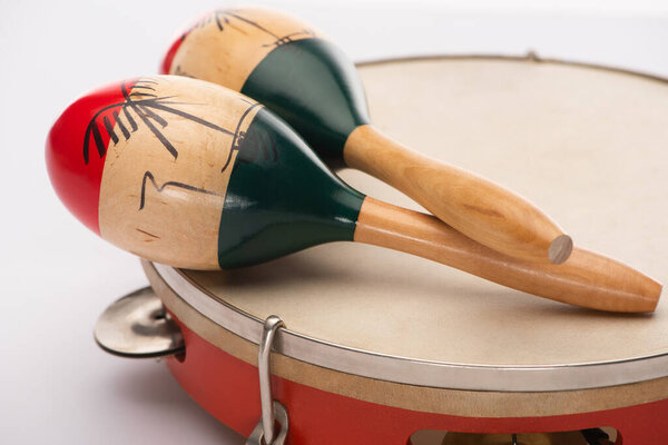 Selective focus of wooden maracas on tambourine on white background