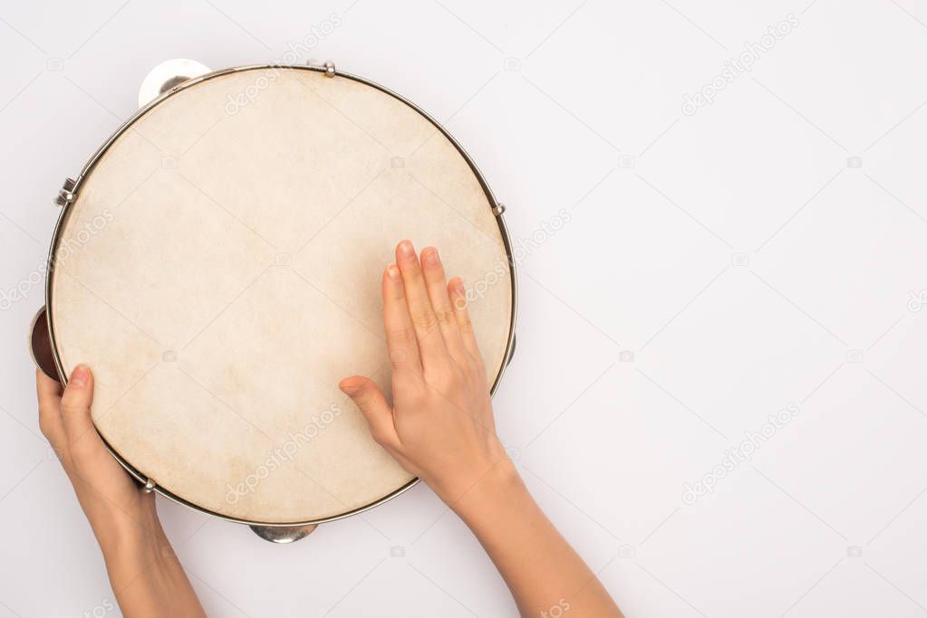 Cropped view of woman playing on tambourine on white background